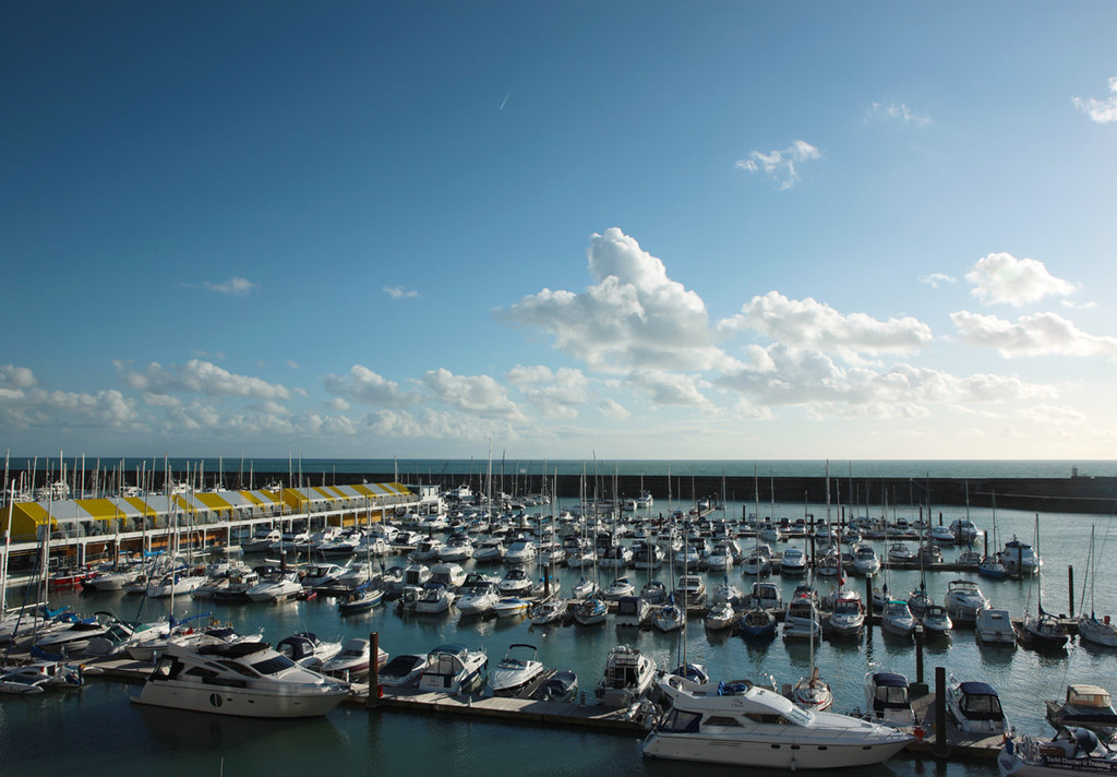 Brighton Marina from a high angle featuring sail boats and yachts moored and the famous yellow and white striped jetty canopy to the left of the image
